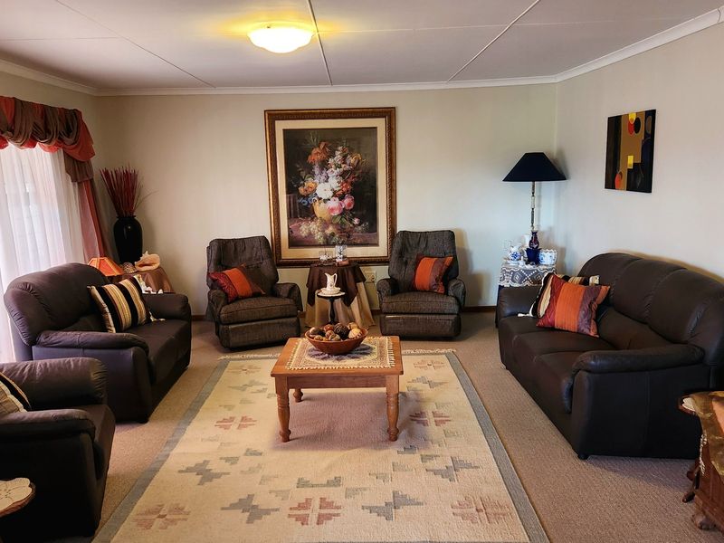 A spacious living room featuring neutral wall tones, carpeted flooring, and a large sliding glass door providing natural light.