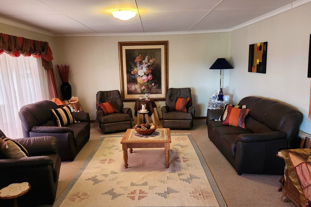 A spacious living room featuring neutral wall tones, carpeted flooring, and a large sliding glass door providing natural light.