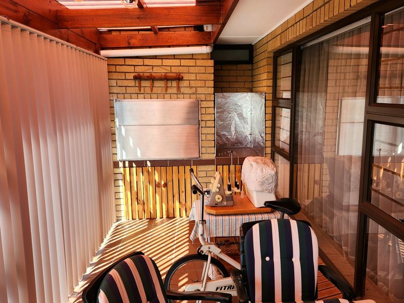 Covered patio area featuring face brick walls, a built-in braai, and timber pergola roofing, providing a functional outdoor entertainment space.
