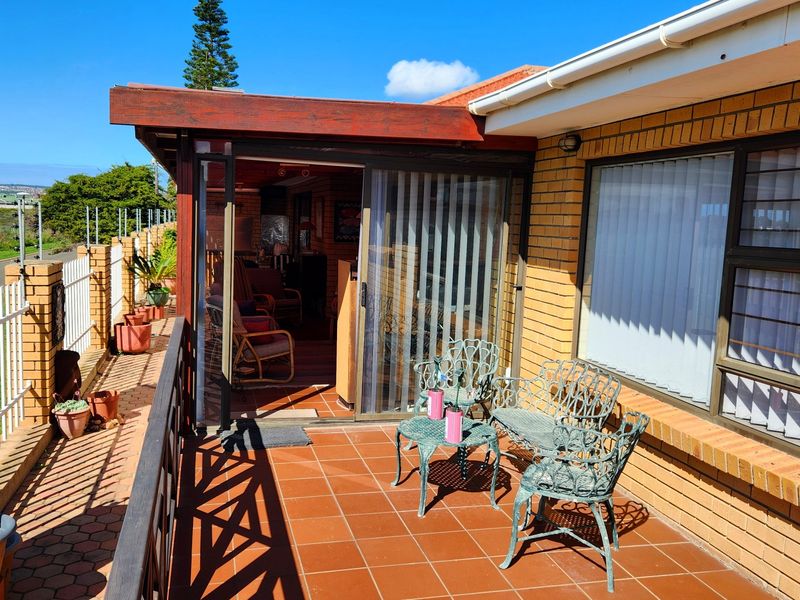 A covered outdoor patio area featuring tiled flooring, brick exterior walls, and sliding glass door access to the interior living space.