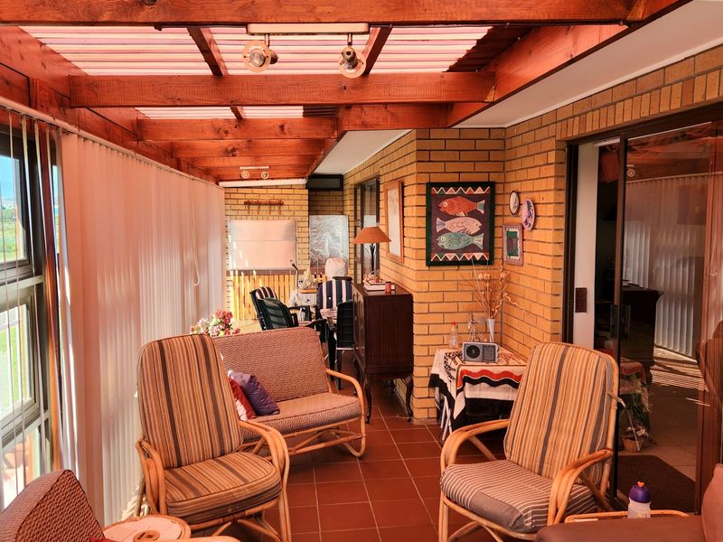Enclosed patio featuring exposed timber beams, translucent roofing, face brick walls, and tiled flooring, providing a versatile indoor-outdoor living space.