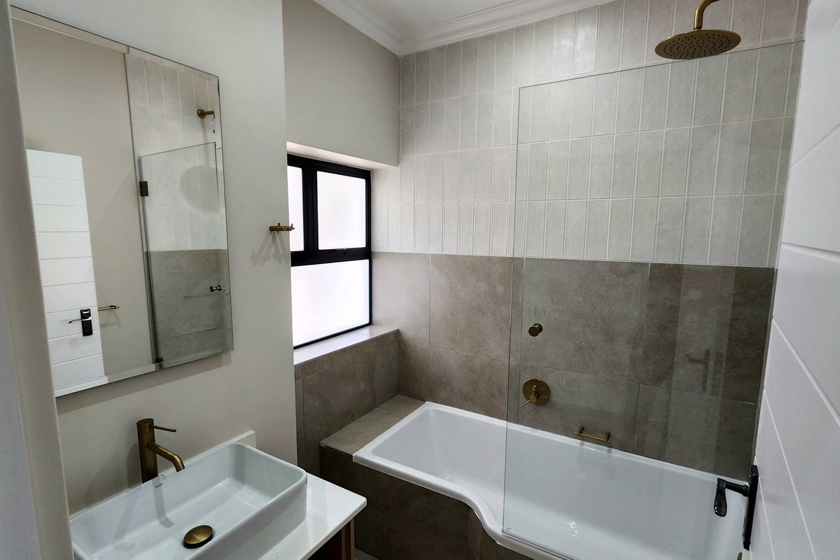 Modern bathroom featuring a vessel sink vanity, brass fixtures, and a shower-over-bath combination with contemporary tiled finishes.