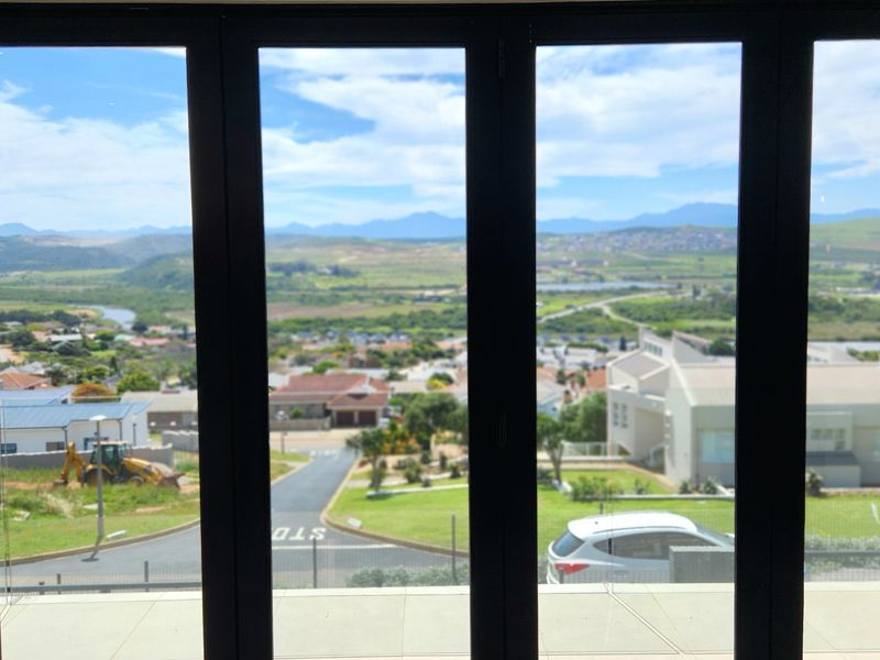 A clear view of the surrounding neighbourhood and distant mountains framed by modern black aluminium stacker doors.