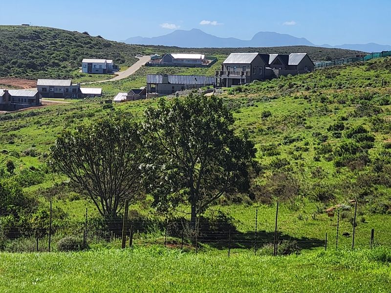 A scenic view of the surrounding residential estate landscape, featuring rolling green hills and established modern homes in the distance.