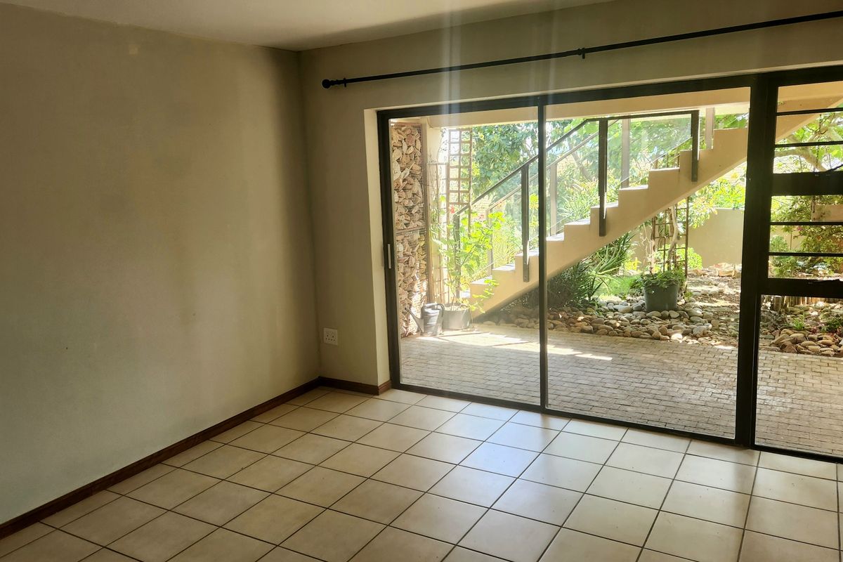 An empty living room featuring ceramic floor tiles and a large sliding glass door providing direct access to an outdoor patio area.