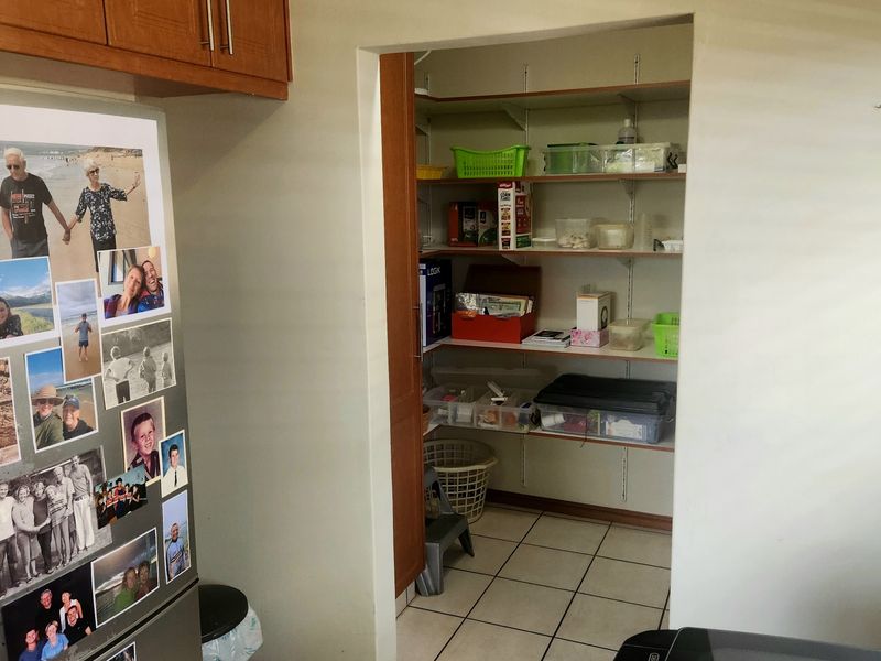 A functional walk-in pantry or scullery area featuring built-in shelving and tiled flooring, providing convenient additional storage space adjacent to the kitchen.