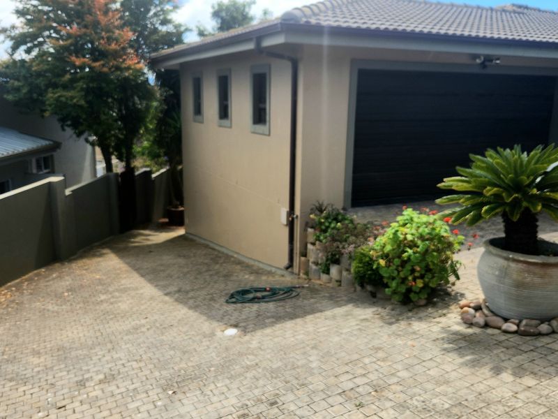 Front exterior view of the property featuring a paved driveway, double garage, and boundary wall.