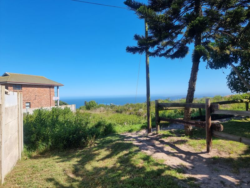 A scenic view of the coastline from the property, featuring natural vegetation and rustic timber fencing.
