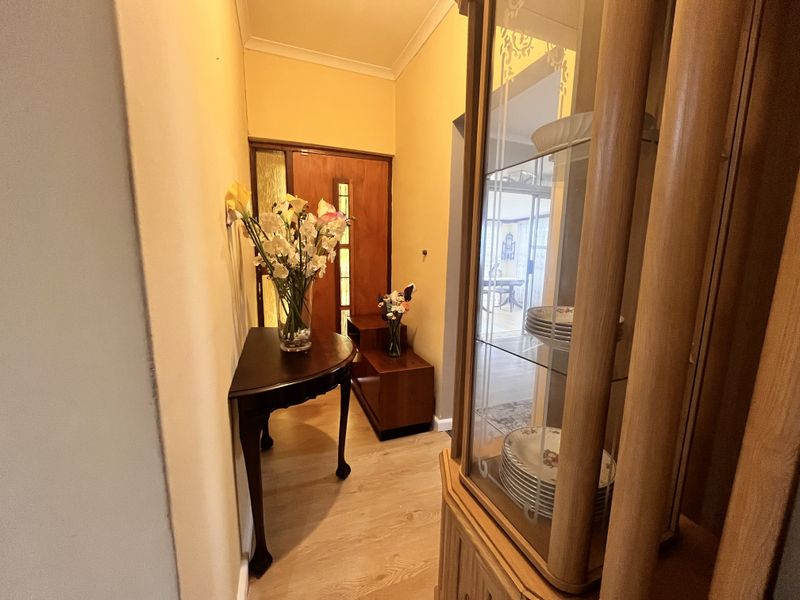 A welcoming entrance hall featuring laminate flooring, a timber front door with glass inserts, and coved ceilings, providing a warm transition into the home.