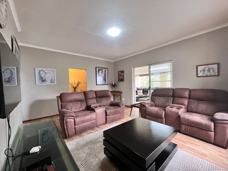 A well-maintained living room featuring laminate flooring, coved ceilings, and a sliding glass door providing access to an adjoining patio area.
