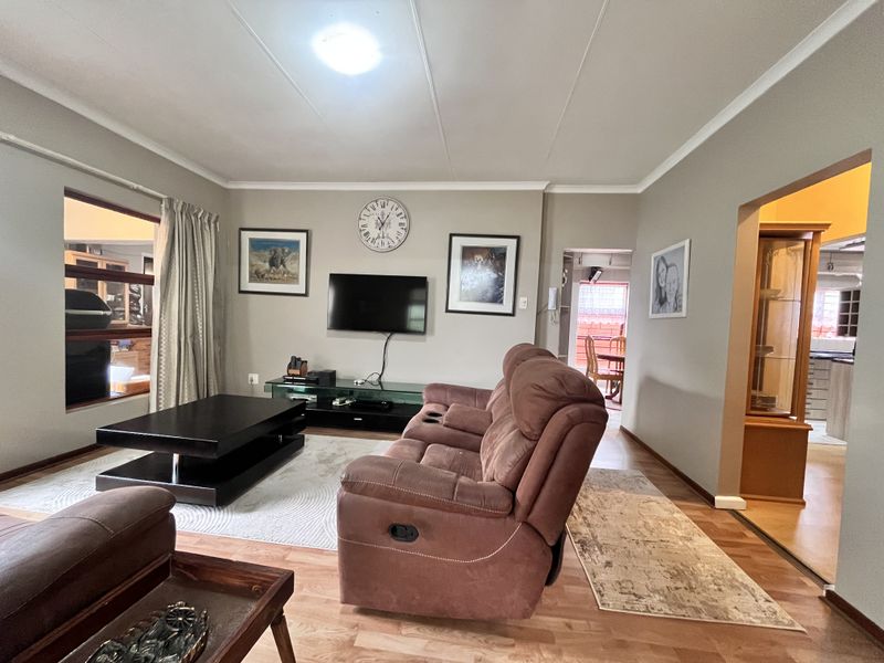 A comfortable living room featuring laminate flooring, coved ceilings, and neutral wall tones, providing a functional and inviting space for relaxation.