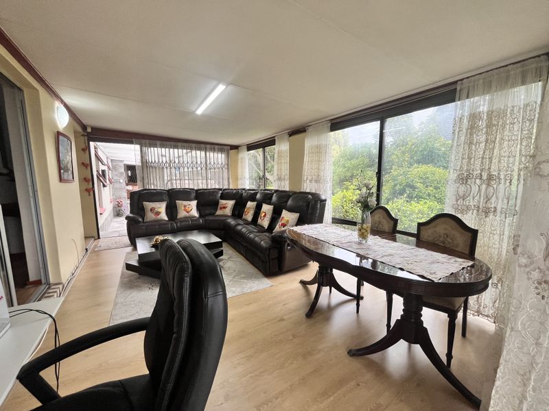Spacious open-plan living and dining area featuring laminate flooring and large sliding glass doors that provide ample natural light and garden access.