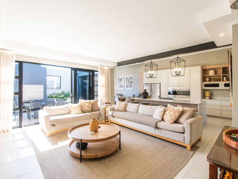 Spacious open-plan living area featuring a modern kitchen with island, sleek cabinetry, and large sliding doors opening to an outdoor patio space.