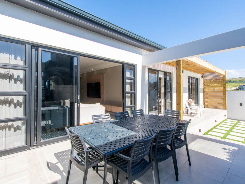 A modern covered patio featuring tiled flooring, a timber pergola, and large sliding glass doors providing seamless indoor-outdoor flow.