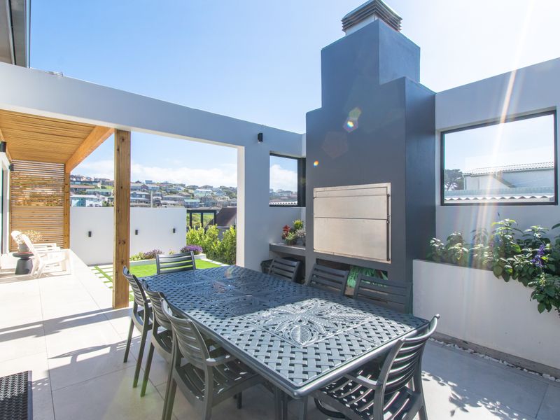Modern covered patio featuring a built-in braai, tiled flooring, timber ceiling accents, and integrated planter boxes, offering a seamless outdoor entertainment space.