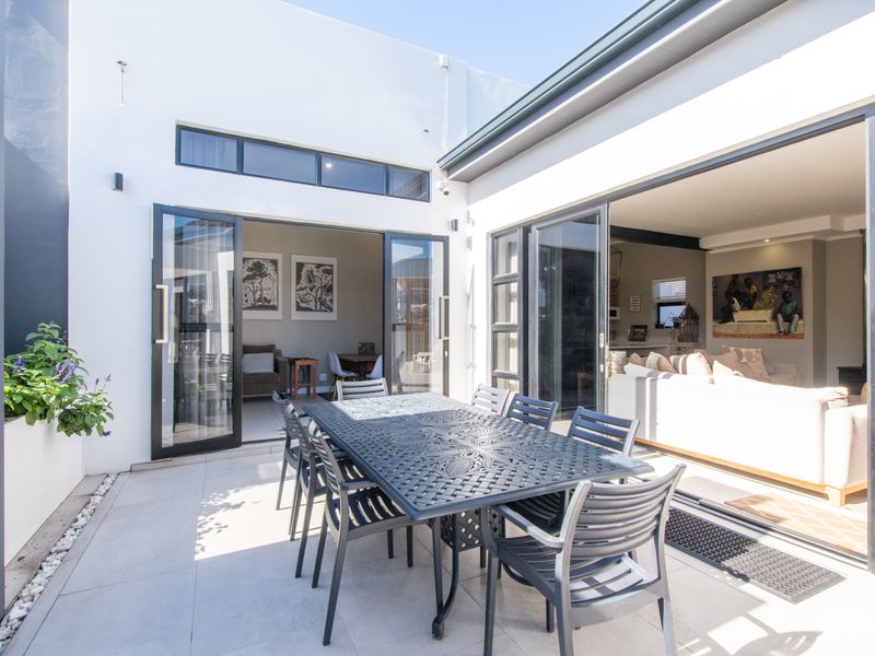 A modern, covered patio area featuring tiled flooring, a built-in fireplace, and large aluminium sliding doors that provide seamless indoor-outdoor flow.