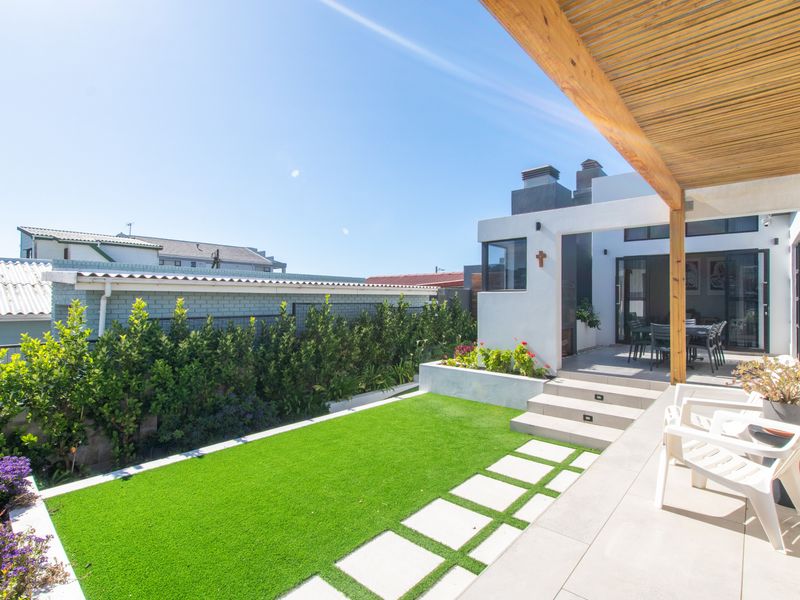 A well-maintained outdoor patio area featuring a timber pergola, tiled flooring, and a landscaped garden with artificial lawn and raised beds.