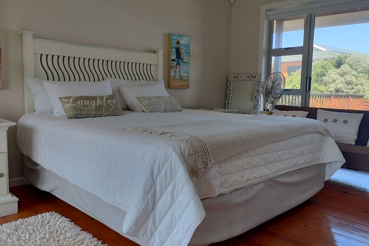 A well-lit bedroom featuring warm timber flooring and large sliding glass doors that provide access to an outdoor area.