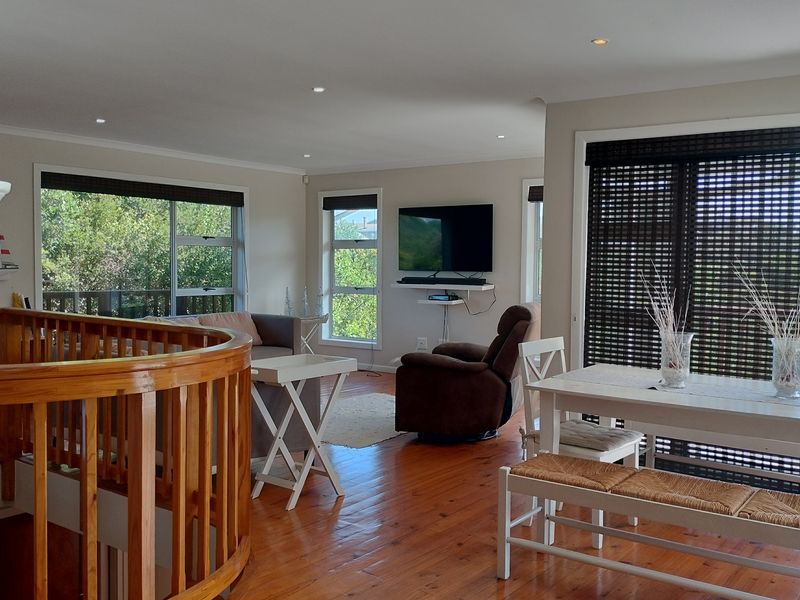 Spacious open-plan living and dining area featuring warm timber flooring, recessed lighting, and large sliding doors leading to an outdoor balcony.