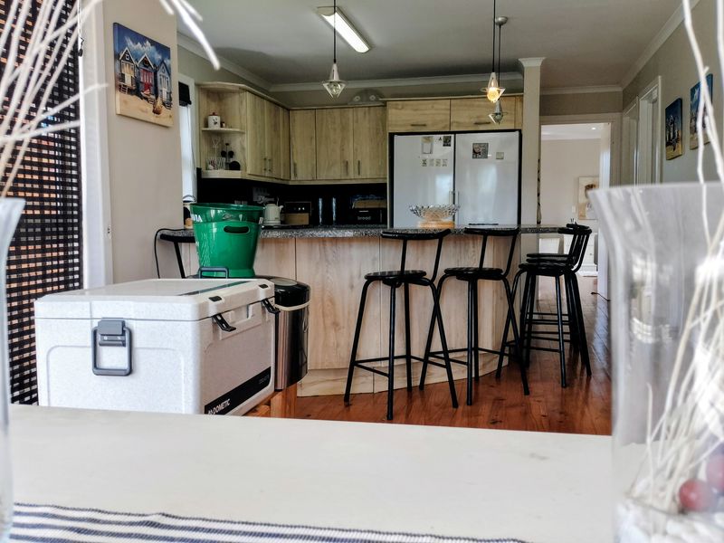 A functional kitchen featuring light wood cabinetry, granite countertops, and a breakfast bar, set against warm hardwood flooring.