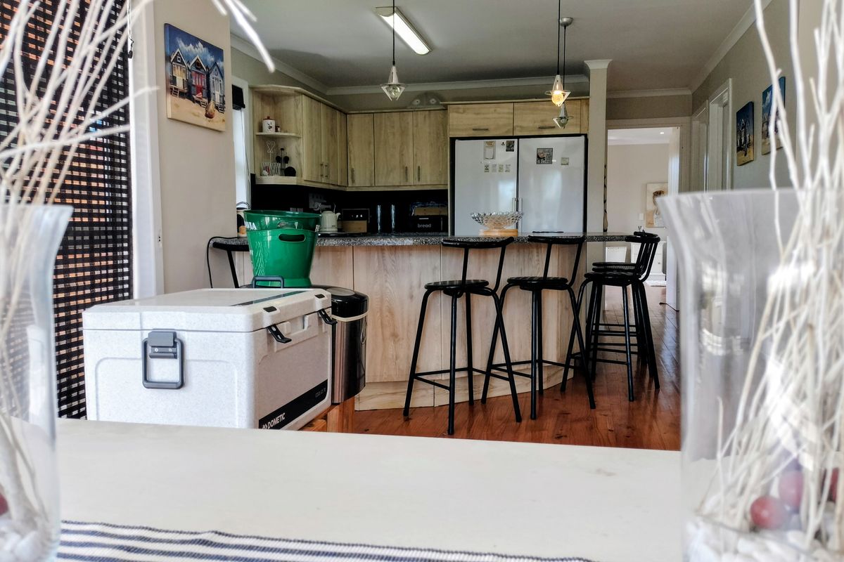 A functional kitchen featuring light wood cabinetry, granite countertops, and a breakfast bar, set against warm hardwood flooring.