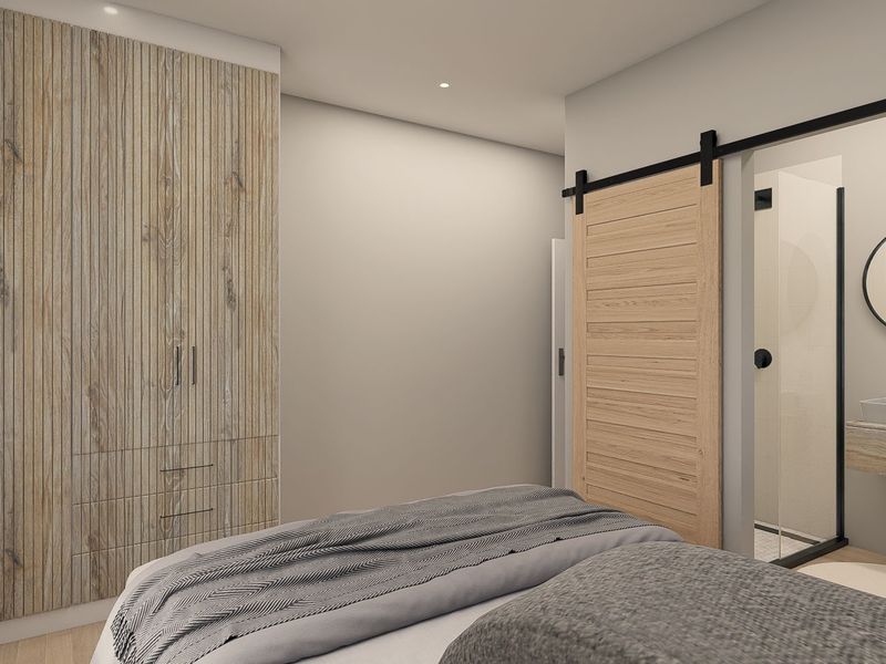 Modern bedroom featuring floor-to-ceiling wood-paneled built-in wardrobes, a sliding barn door leading to an en-suite bathroom with a floating vanity and walk-in shower.