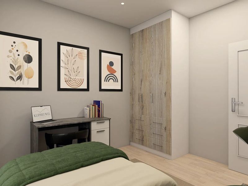 A modern bedroom featuring light laminate flooring, neutral wall tones, and a built-in wardrobe with wood-grain finish doors.