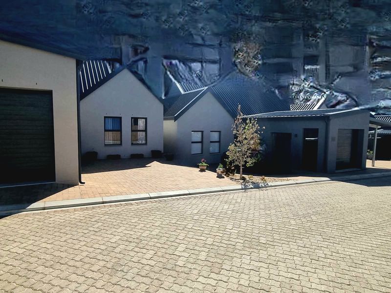 Front elevation of a modern cottage featuring a paved driveway, metal roofing, and integrated garage access.
