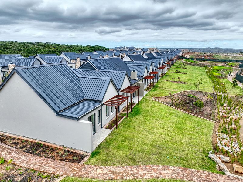 Aerial view of a modern cottage development featuring uniform metal roofing, timber pergolas, and landscaped garden areas with brick pathways.