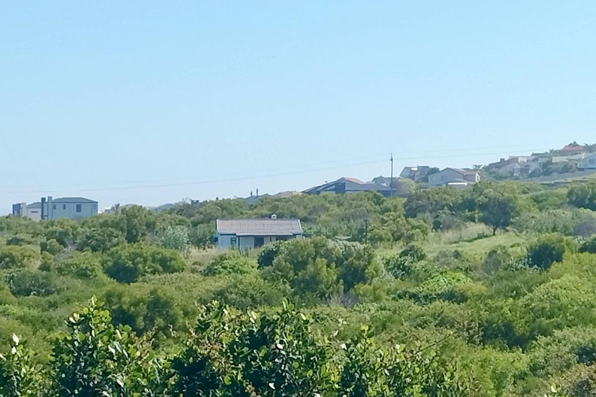 A distant view of a small residential property nestled within natural coastal vegetation and surrounding landscape.