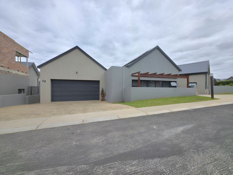 Modern single-story residence featuring a double garage, paved driveway, and a timber pergola over the front entrance area.