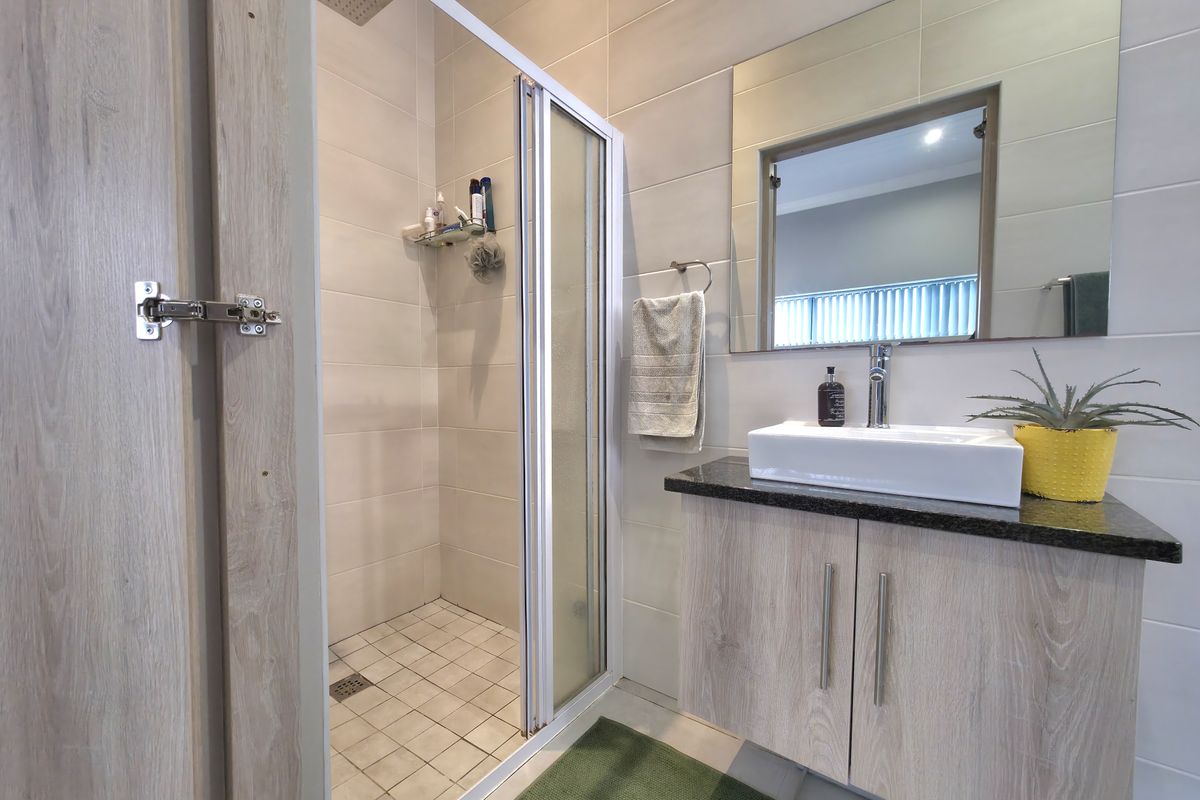 Modern bathroom featuring a glass-enclosed shower with a rain shower head, a vanity with a granite countertop, and a contemporary vessel sink.