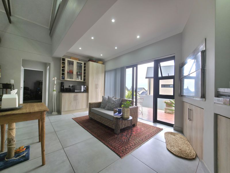 Modern living area featuring tiled floors, recessed lighting, built-in cabinetry, and a built-in braai, with direct access to an outdoor patio.