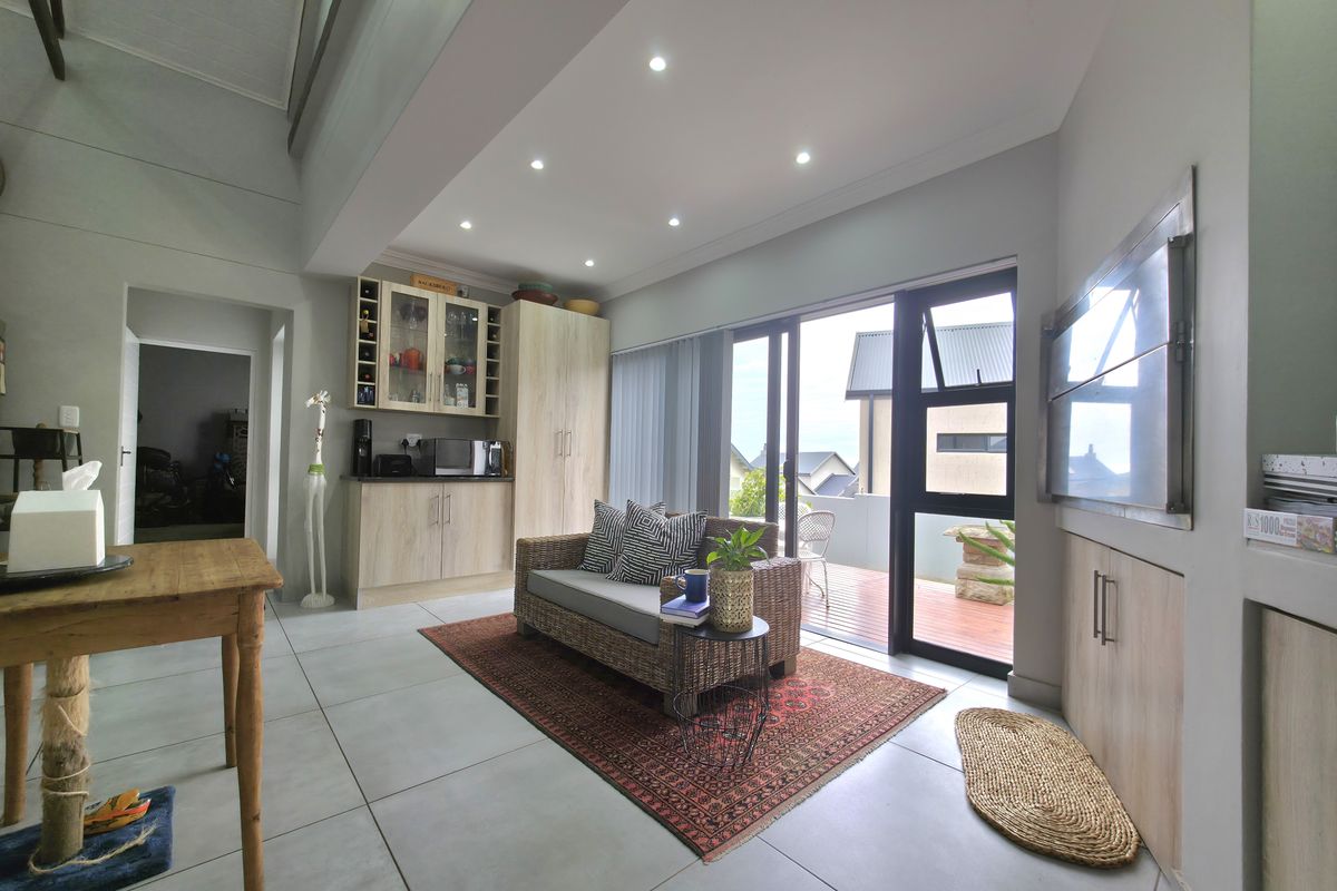 Modern living area featuring tiled floors, recessed lighting, built-in cabinetry, and a built-in braai, with direct access to an outdoor patio.