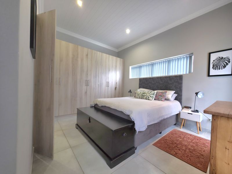 A well-maintained bedroom featuring extensive built-in light wood cabinetry, tiled flooring, and a modern tongue and groove ceiling with recessed lighting.