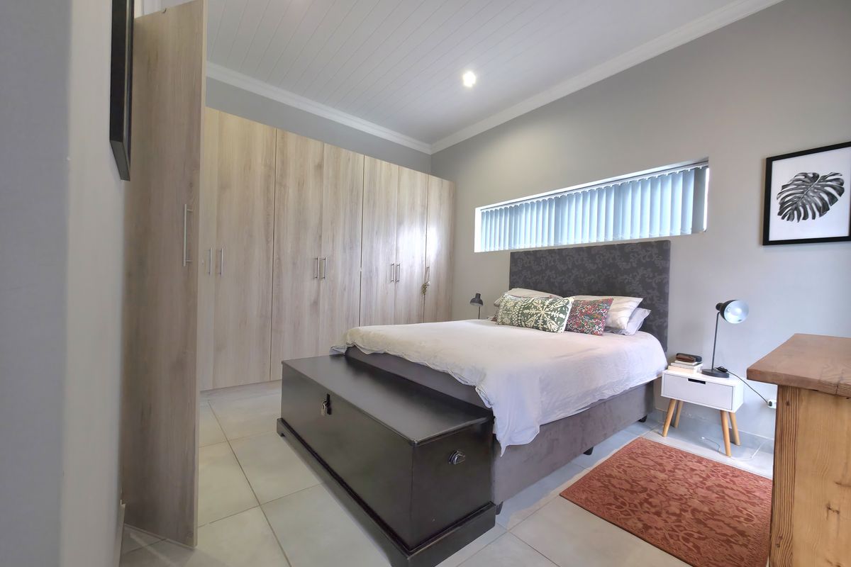 A well-maintained bedroom featuring extensive built-in light wood cabinetry, tiled flooring, and a modern tongue and groove ceiling with recessed lighting.