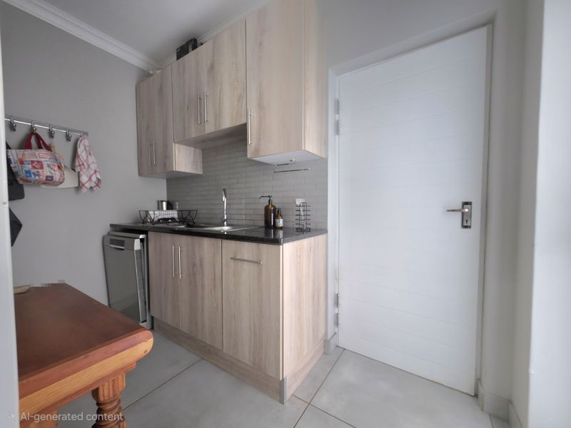 A compact and functional scullery featuring light wood-finish cabinetry, a subway tile backsplash, and modern tiled flooring.