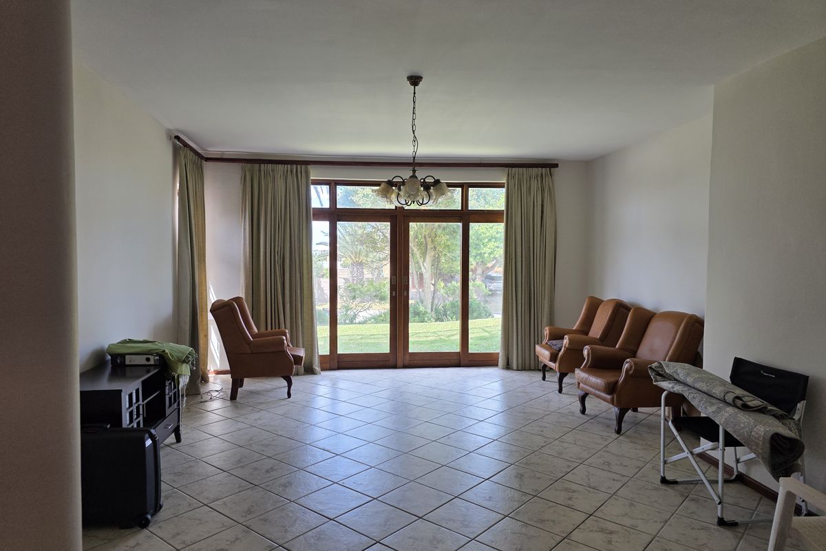 Spacious living room featuring tiled flooring and large wooden sliding doors that provide direct access to the garden.