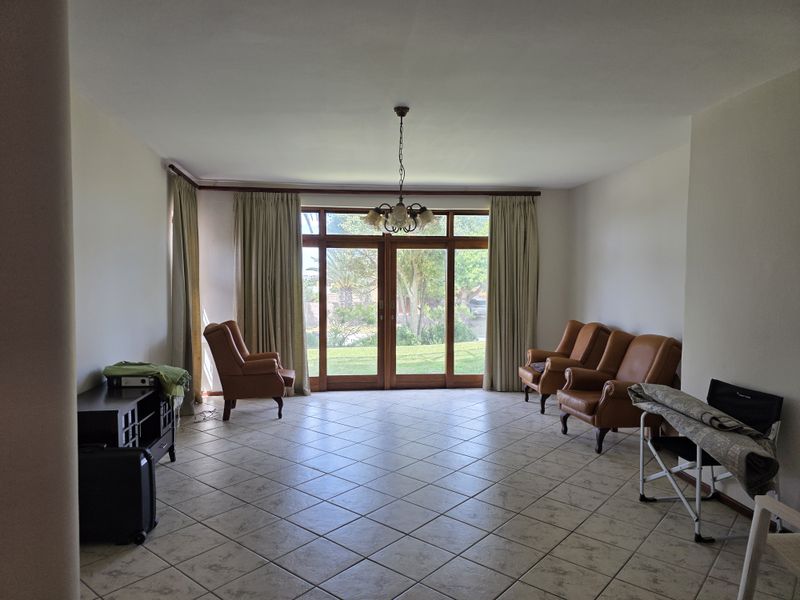 Spacious living room featuring tiled flooring and large wooden sliding doors that provide direct access to the garden.