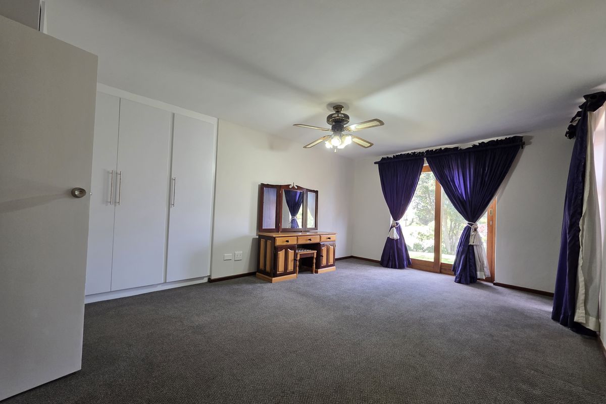Spacious bedroom featuring built-in cupboards, a ceiling fan, and a sliding glass door providing access to the outdoors.