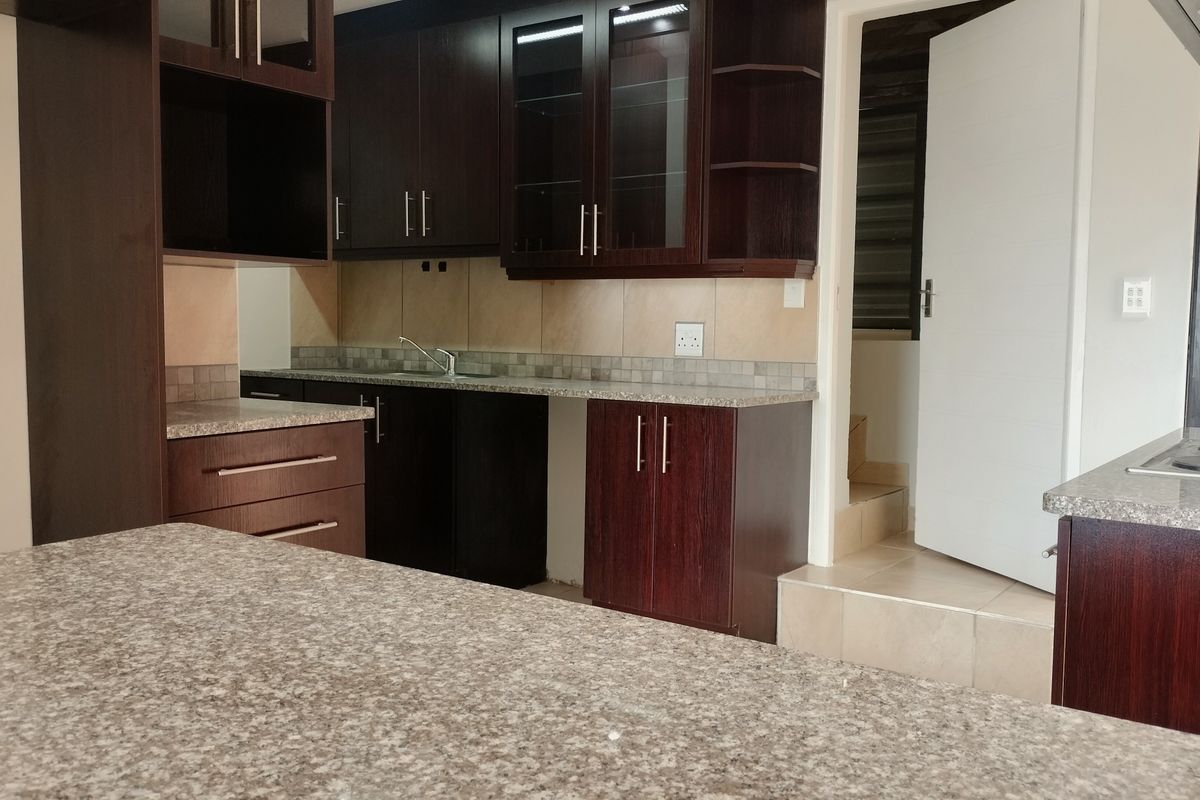 A functional kitchen featuring dark wood cabinetry, granite countertops, a tiled backsplash, and integrated cooking appliances.