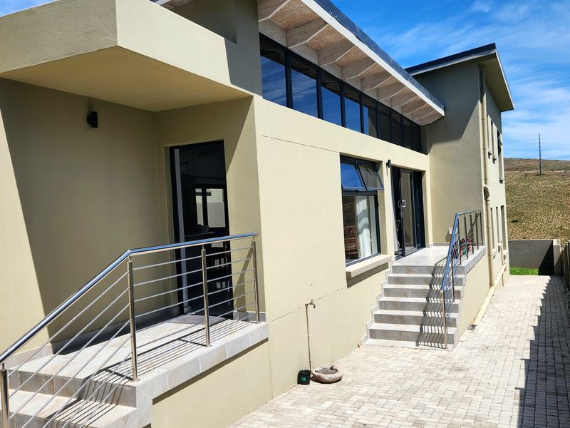 Rear exterior view of the duet property featuring a paved walkway, tiled stairs with stainless steel balustrades, and modern clerestory windows.
