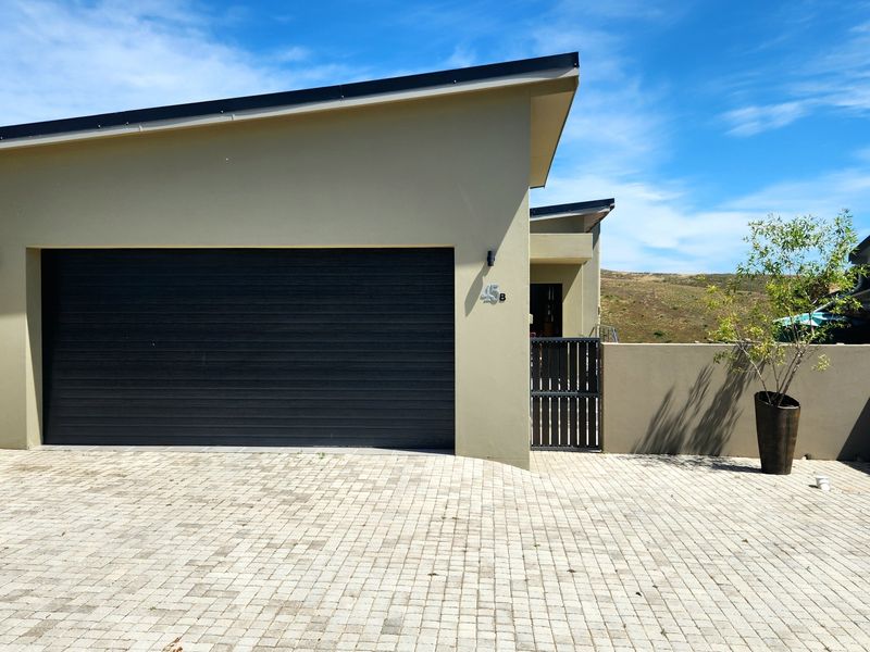 Front elevation of a modern duet property featuring a single garage, paved driveway, and secure pedestrian gate access.