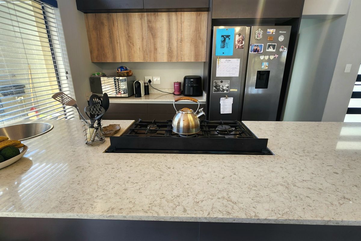 Modern kitchen featuring a spacious quartz island with an integrated gas hob, sleek cabinetry, and a contemporary undermount sink.