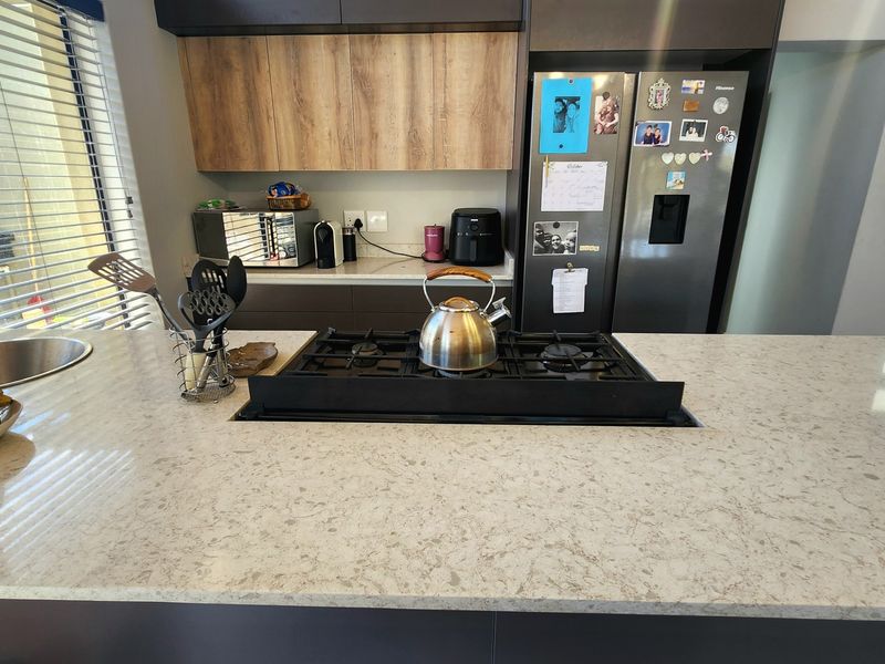 Modern kitchen featuring a spacious quartz island with an integrated gas hob, sleek cabinetry, and a contemporary undermount sink.