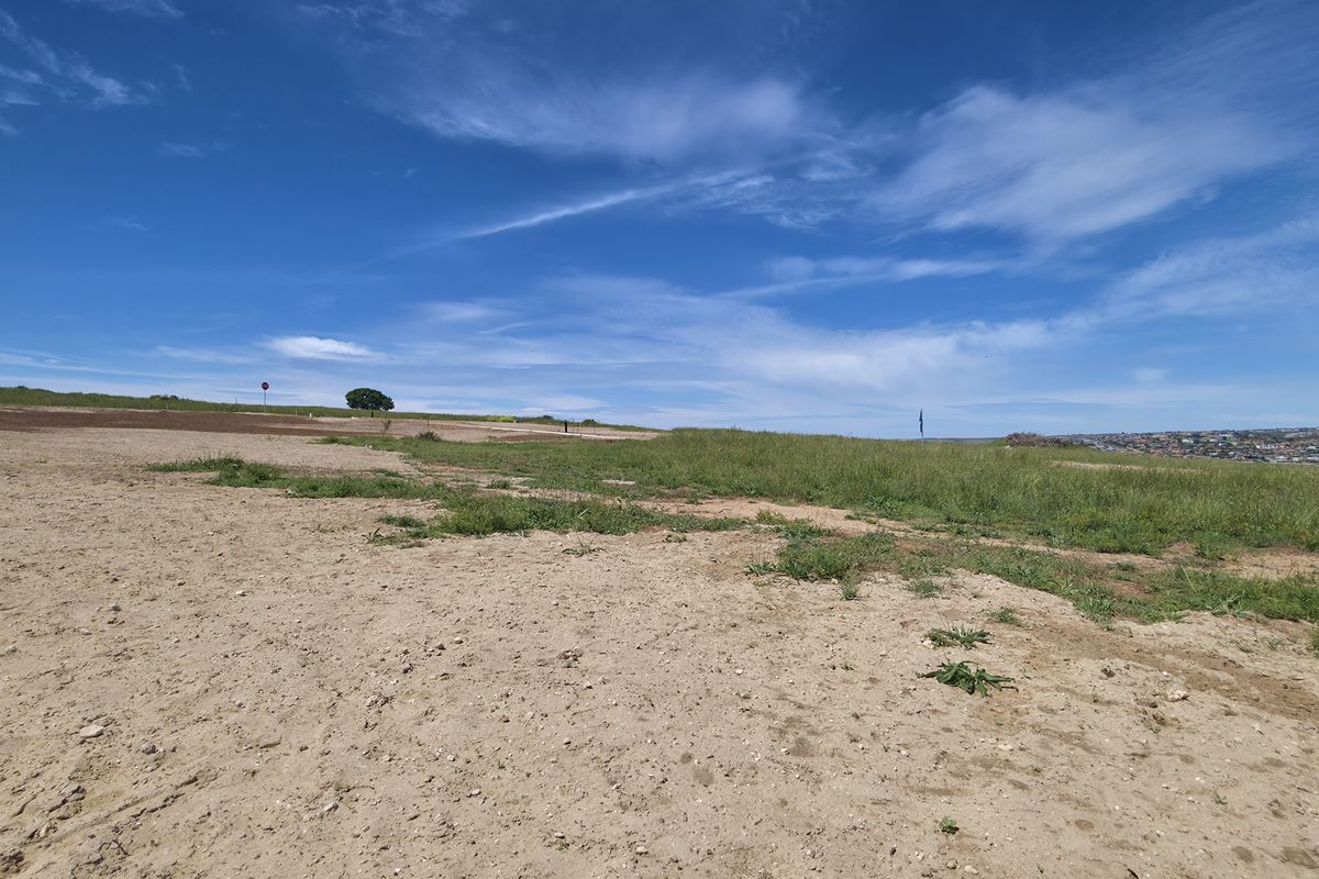 A wide-angle view of a vacant residential plot featuring natural grassland and open terrain, suitable for future development.