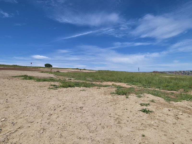 A wide-angle view of a vacant residential plot featuring natural grassland and open terrain, suitable for future development.