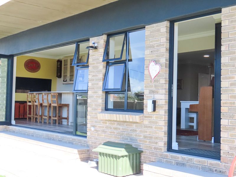 A covered patio area featuring modern bi-fold doors and casement windows, providing seamless indoor-outdoor flow to the interior living space.