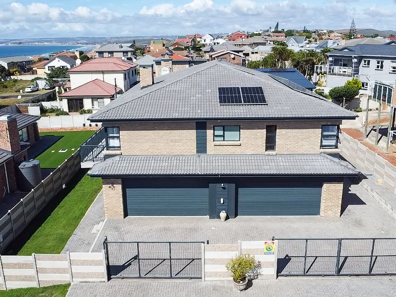Aerial view of a modern double-story brick house featuring a tiled roof, solar panels, a double garage, and a secure paved driveway.