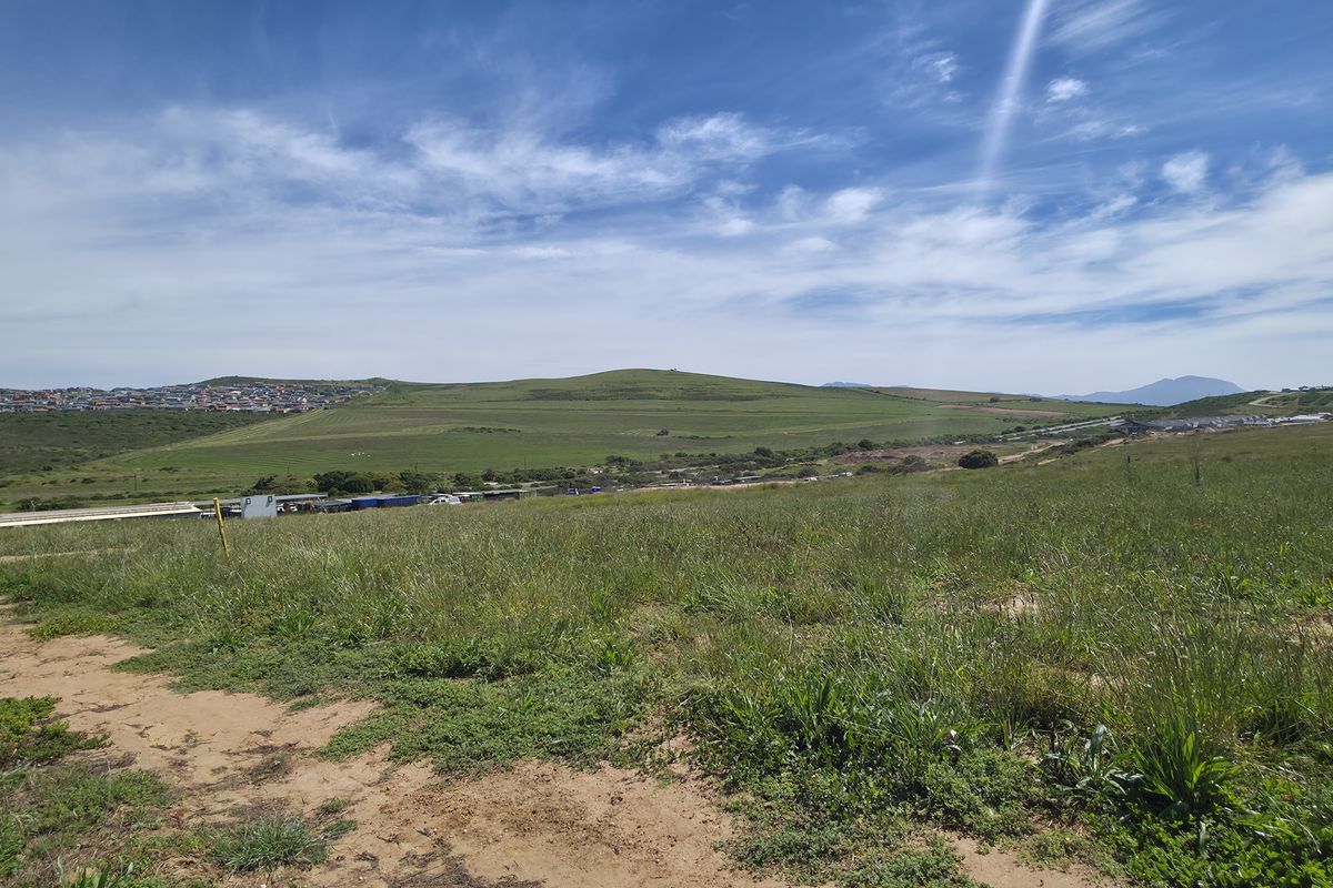 A wide-angle view of the vacant residential land, showcasing the surrounding landscape and distant neighborhood.